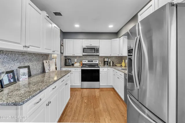 a kitchen with granite countertop a refrigerator stove and sink
