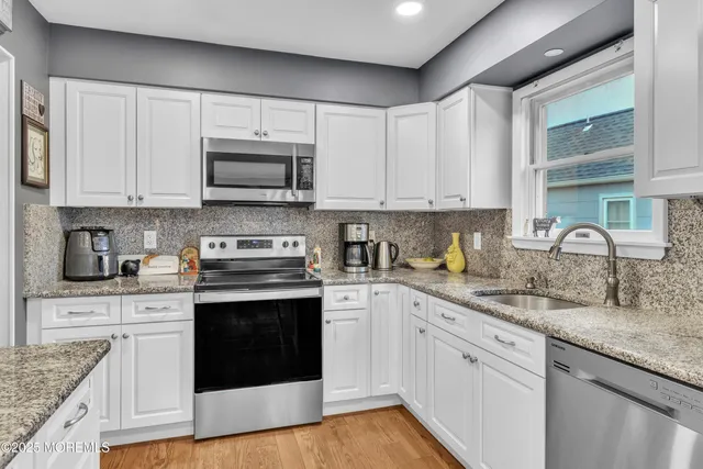 a kitchen with granite countertop a sink cabinets and stainless steel appliances