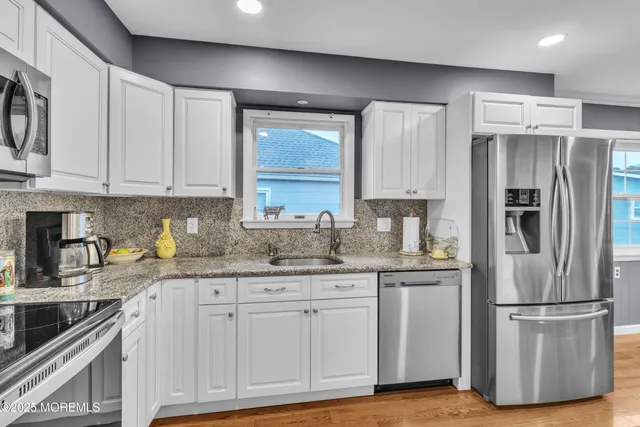 a kitchen with granite countertop a refrigerator sink and cabinets