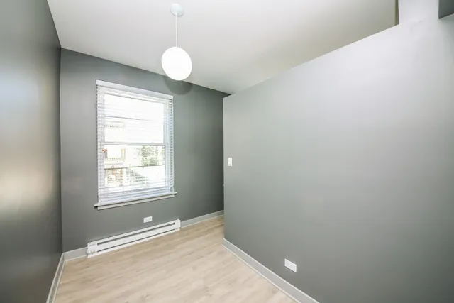 a view of an empty room with window and wooden floor