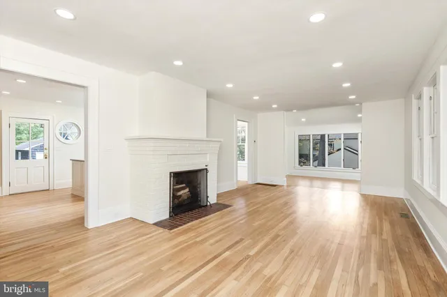 a view of an empty room with wooden floor fireplace and a window
