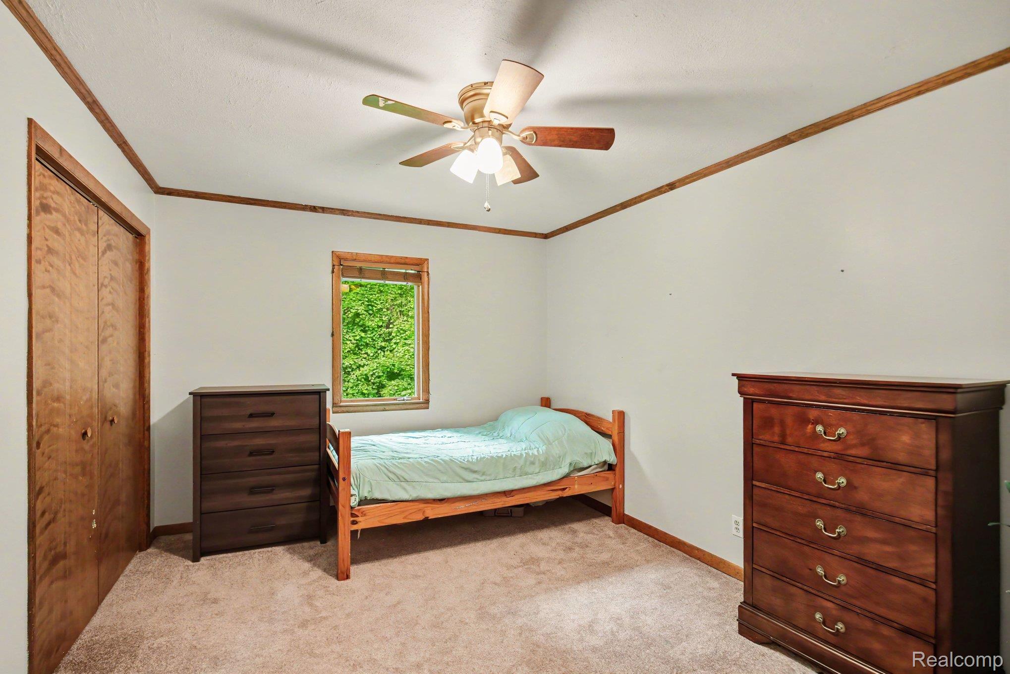 1646 Boy Scout Road Caro, MI 48723 - Photo 12 of 28 Carpeted room featuring a ceiling fan with integrated lighting, wood trim details, and a window with wood framing