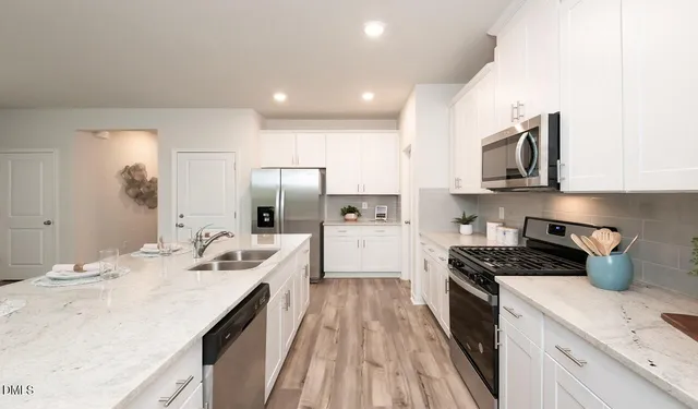 a kitchen with stainless steel appliances a stove a sink a refrigerator and cabinets