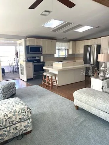 a large white kitchen with kitchen island a stove a sink dishwasher and wooden floor