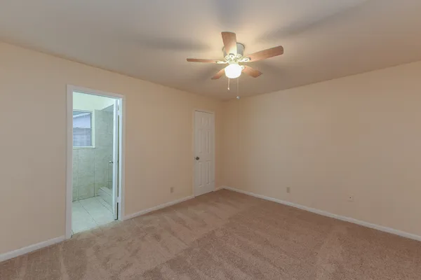 an empty room with a ceiling fan and a window