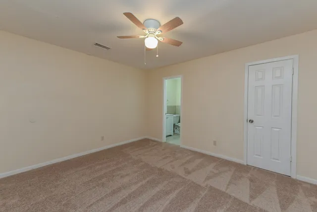 an empty room with closet and ceiling fan