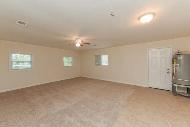 an empty room with windows and fan
