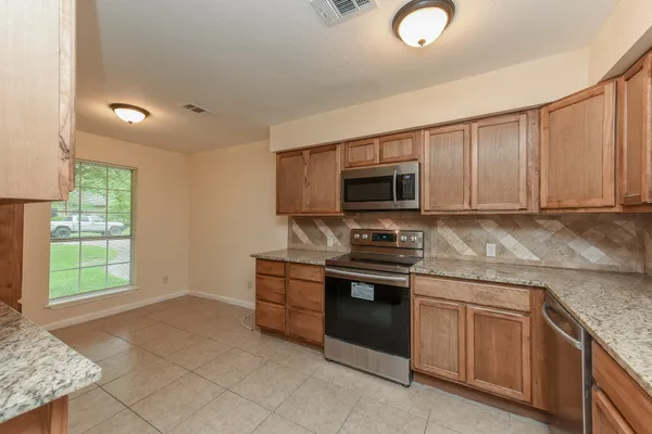 a kitchen with stainless steel appliances granite countertop a stove top oven a sink dishwasher and a microwave oven with white cabinets