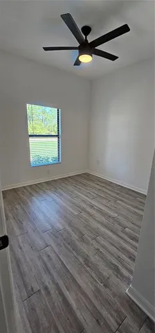 a view of an empty room with wooden floor and closet
