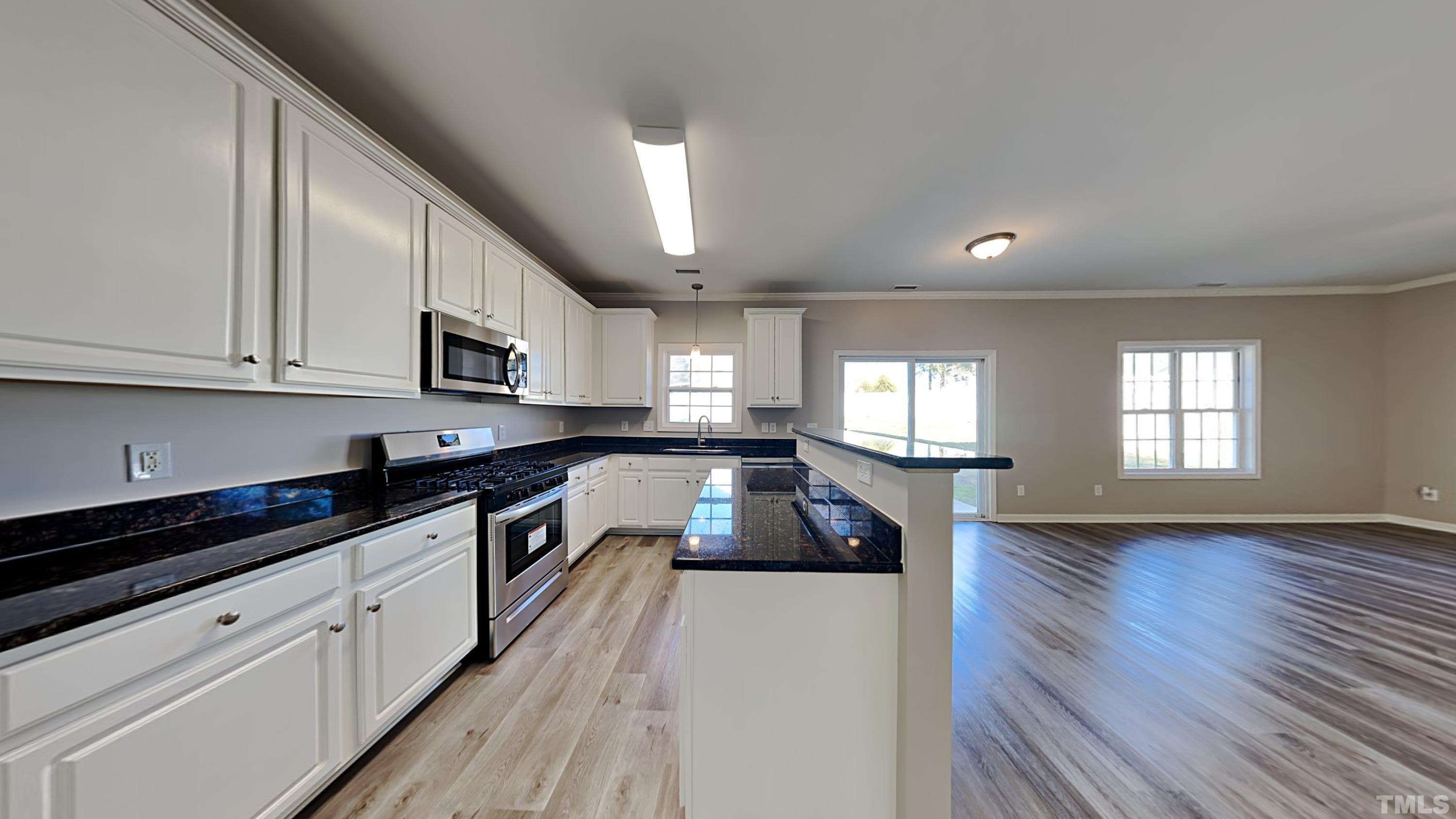 3602 Rendition Street Raleigh, NC 27610 - Photo 5 of 13 a large kitchen with granite countertop a stove top oven a sink dishwasher and white cabinets with wooden floor