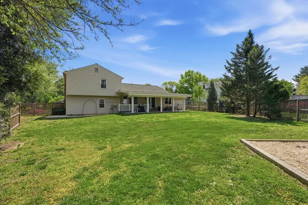 a view of a house with a yard and a large tree