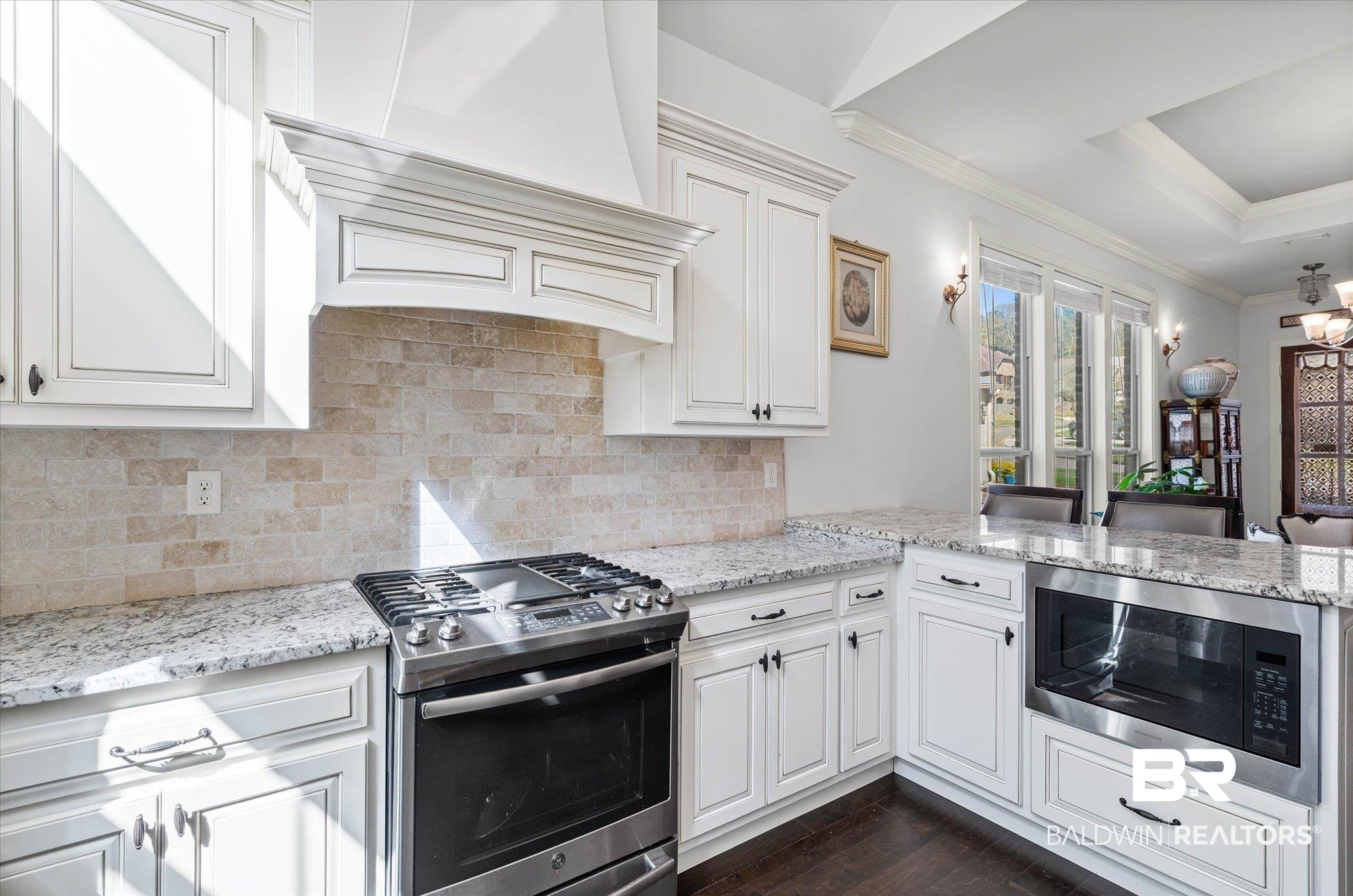 3528 Rue Royal Mobile, AL 36693 - Photo 14 of 53 Kitchen featuring stainless steel appliances, ornamental molding, light stone countertops, white cabinets, and a raised ceiling