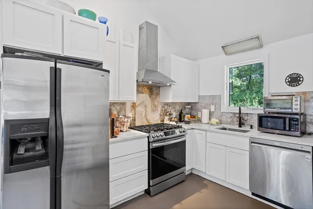 a kitchen with stainless steel appliances white cabinets and a stove top oven