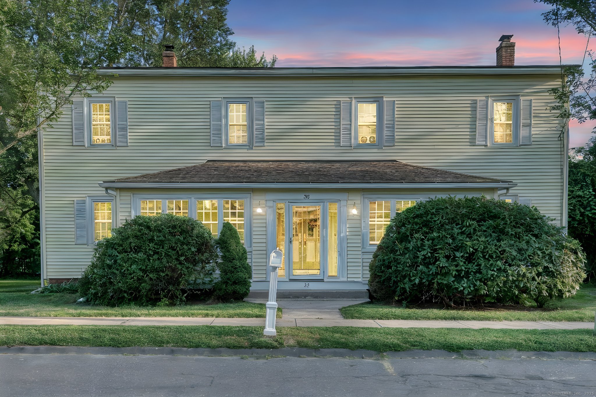 a front view of a house with a yard and potted plants