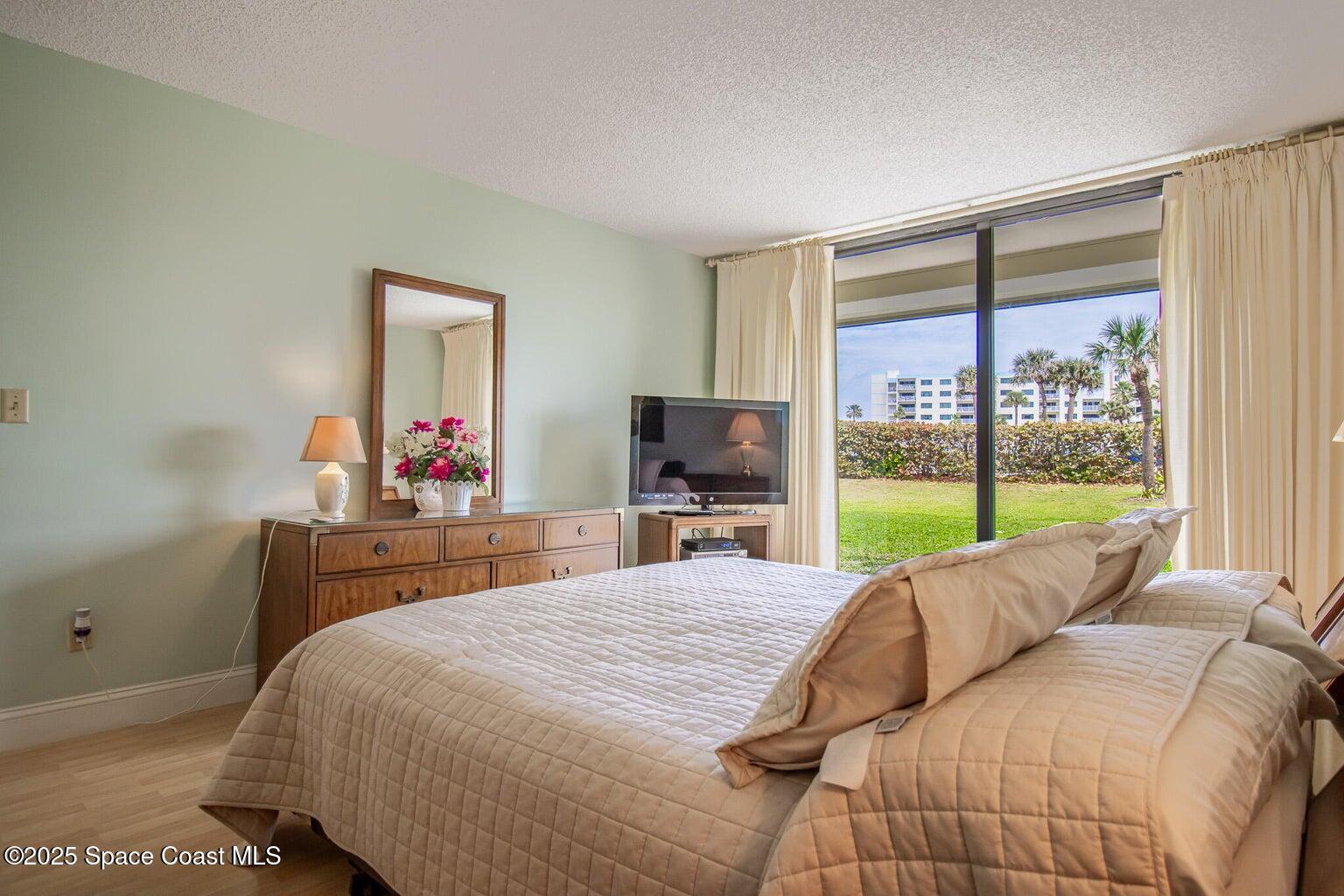 840 North Atlantic Avenue, Unit C103 Cocoa Beach, FL 32931 - Photo 16 of 30 a bedroom with a bed and large windows