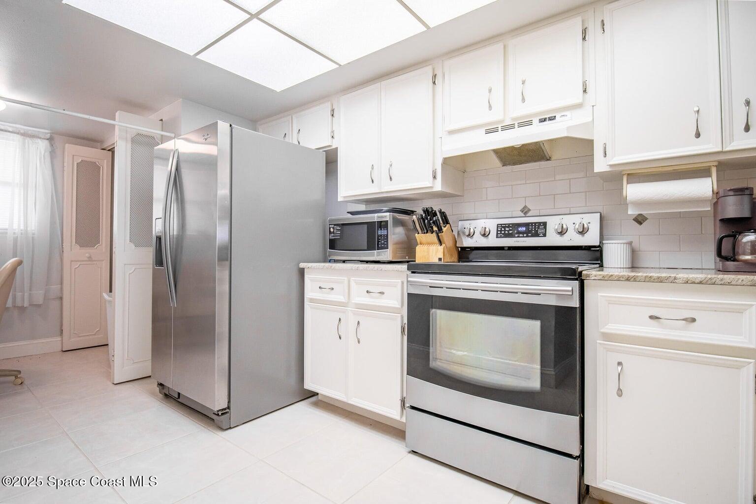840 North Atlantic Avenue, Unit C103 Cocoa Beach, FL 32931 - Photo 3 of 30 a kitchen with stainless steel appliances granite countertop a refrigerator sink and stove