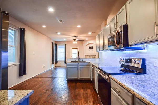 a kitchen with stainless steel appliances granite countertop wooden cabinets a sink dishwasher a stove and a refrigerator