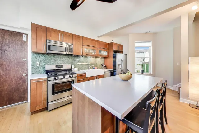 a kitchen with stainless steel appliances a stove a sink a microwave a dining table and chairs