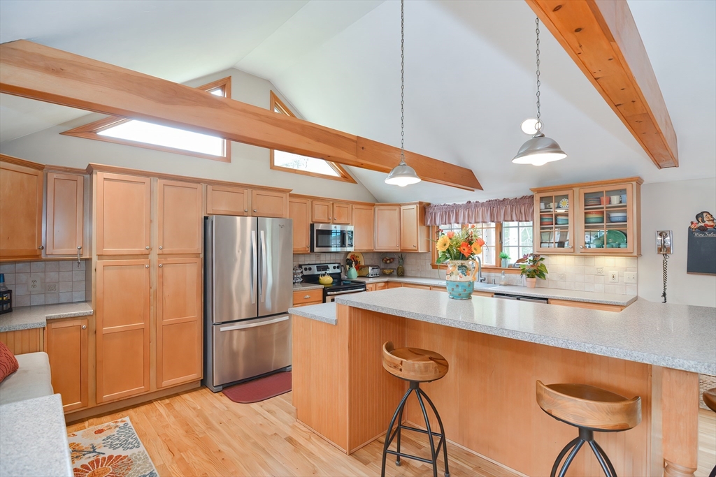 143 South Meadow Road Plymouth, MA 02360 - Photo 9 of 35 a kitchen with stainless steel appliances granite countertop a refrigerator a sink dishwasher a stove a dining table and chairs with wooden floor