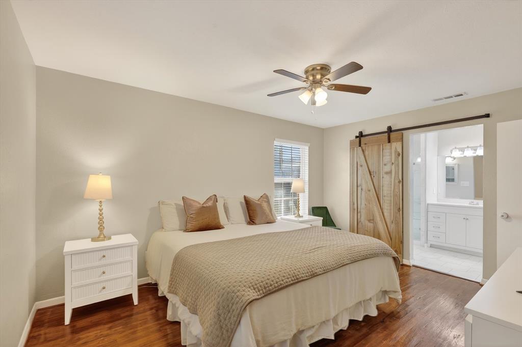 2920 Sharpview Lane Dallas, TX 75228 - Photo 24 of 34 Bedroom featuring a barn door, dark wood-style floors, a ceiling fan, and ensuite bath