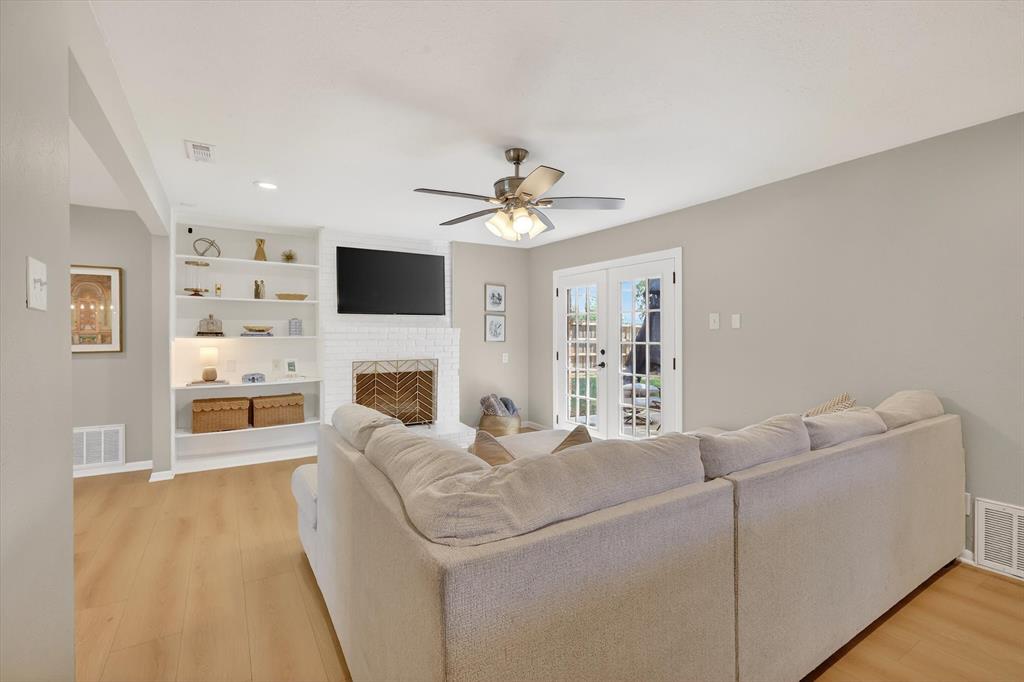 2920 Sharpview Lane Dallas, TX 75228 - Photo 6 of 34 Living room with french doors, a ceiling fan, light wood finished floors, a brick fireplace, and recessed lighting