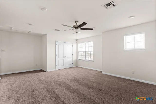 an empty room with windows and fan