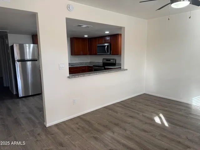 a view of kitchen with stainless steel appliances wooden floor and chair