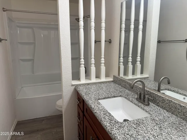 a bathroom with a granite countertop bathtub sink vanity and toilet