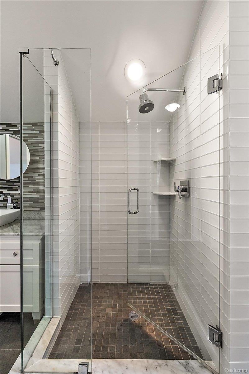 1051 Devonshire Road Grosse Pointe, MI 48230 - Photo 63 of 99 Glass-enclosed shower with white subway tile walls, dark mosaic tile flooring, and integrated shelving