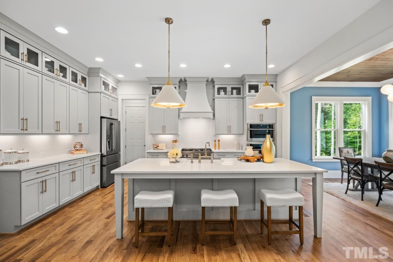 7204 Sing Along Court Raleigh, NC 27613 - Photo 20 of 46 a kitchen with stainless steel appliances kitchen island granite countertop a dining table chairs and white cabinets