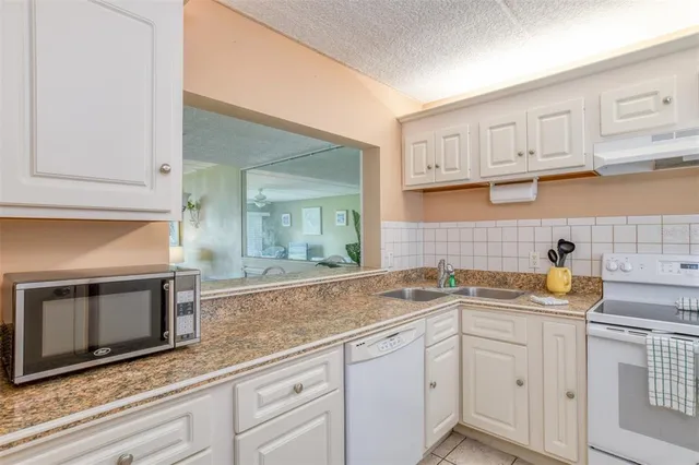 a kitchen with stainless steel appliances granite countertop white cabinets and a sink