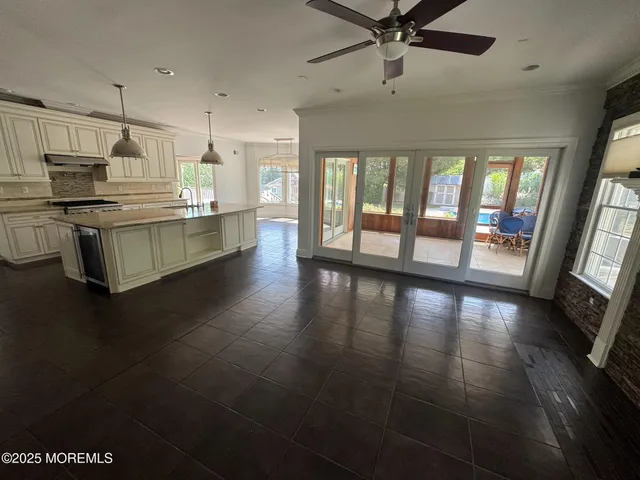 a kitchen with stainless steel appliances a large window a oven a sink with a dining table and chairs