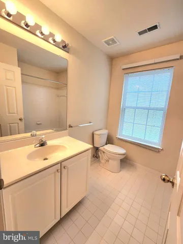 a bathroom with a granite countertop sink a toilet a mirror and shower