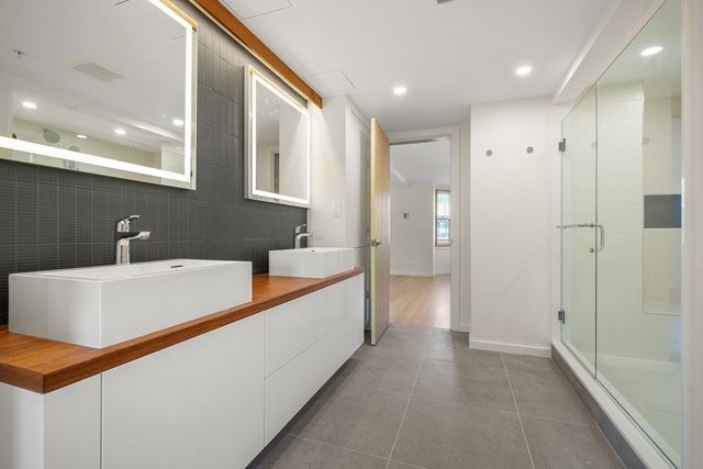 a large white bathroom with a tub a sink and a large mirror
