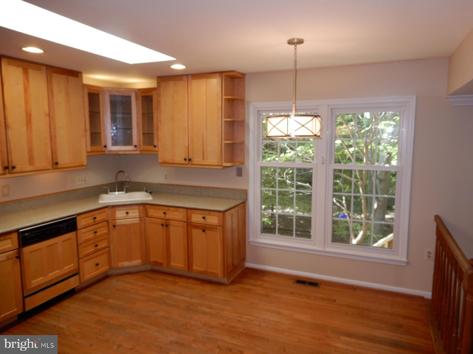 7014 Maple Tree Lane Springfield, VA 22152 - Photo 11 of 56 a kitchen with stainless steel appliances granite countertop wooden cabinets a sink a stove a dining table and chairs