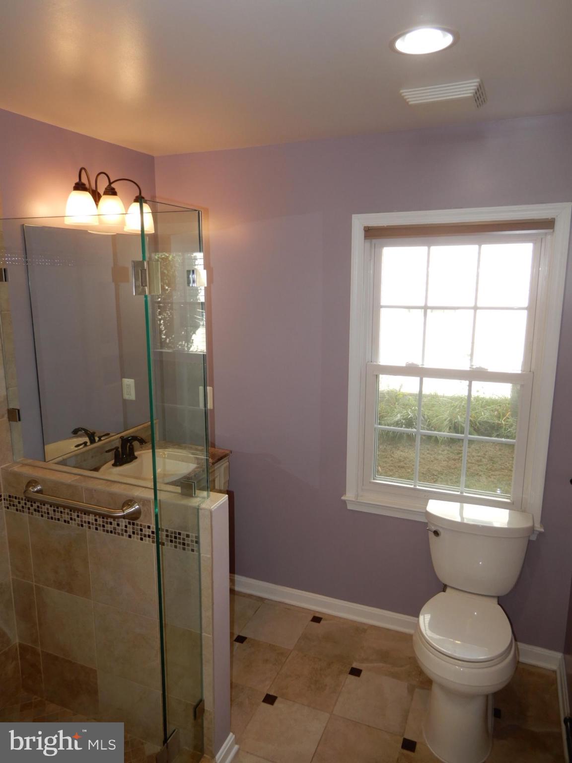 7014 Maple Tree Lane Springfield, VA 22152 - Photo 17 of 56 a bathroom with a toilet mirror vanity and a shower