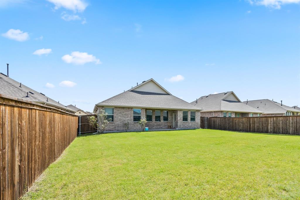 753 Lombard Lane Forney, TX 75126 - Photo 23 of 25 Back of house with brick siding, a fenced backyard, and roof with shingles