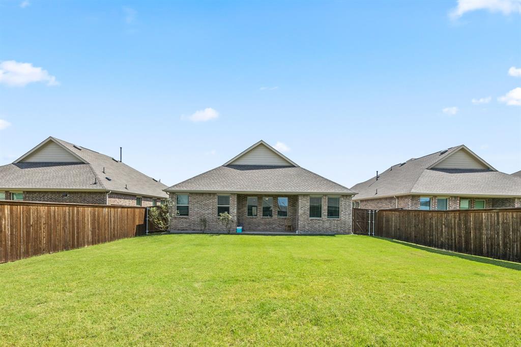753 Lombard Lane Forney, TX 75126 - Photo 24 of 25 Rear view of house featuring brick siding, a fenced backyard, and roof with shingles