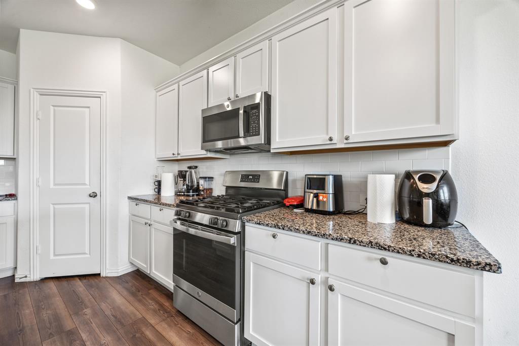 753 Lombard Lane Forney, TX 75126 - Photo 8 of 25 Kitchen with appliances with stainless steel finishes, backsplash, dark stone countertops, dark wood finished floors, and white cabinetry