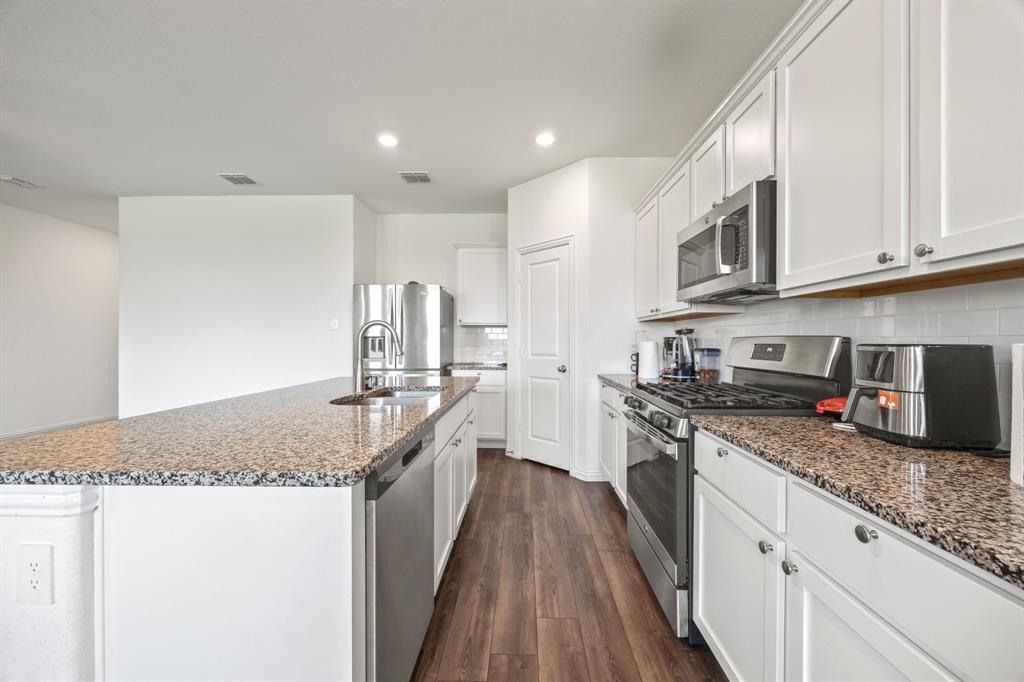 753 Lombard Lane Forney, TX 75126 - Photo 9 of 25 Kitchen featuring stainless steel appliances, dark wood-style floors, recessed lighting, decorative backsplash, and a center island with sink