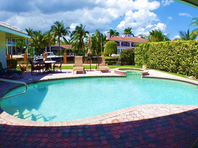 827 Northeast 33rd Street Boca Raton, FL 33431 - Photo 24 of 25 a view of a swimming pool with lawn chairs under an umbrella
