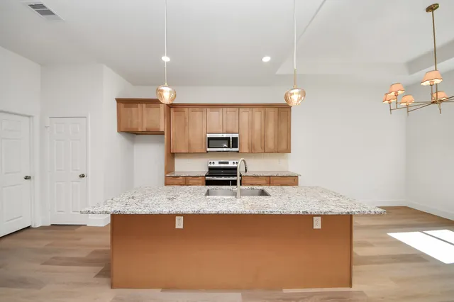 a kitchen with stainless steel appliances granite countertop a sink a stove and a granite counter top