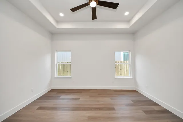 an empty room with wooden floor cabinet and windows