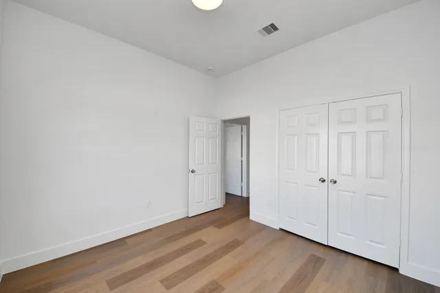 an empty room with wooden floor and closet area