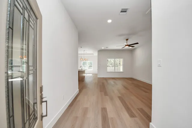 a view of an empty room with wooden floor and a window