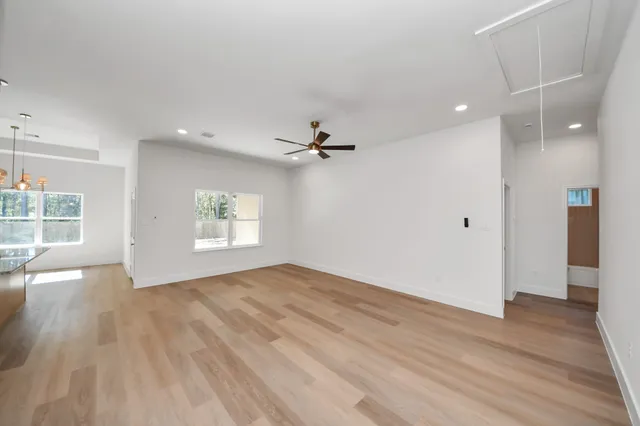 an empty room with wooden floor a ceiling fan and windows