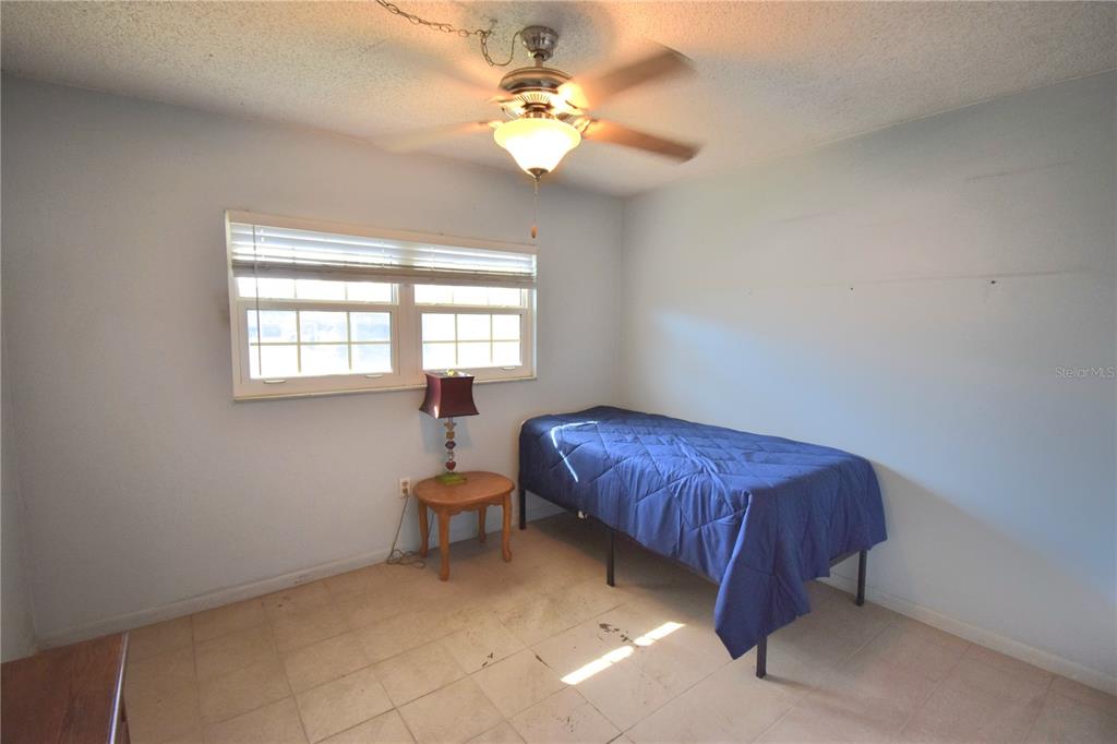 952 Virginia Street, Unit 107 Dunedin, FL 34698 - Photo 4 of 15 a spacious bedroom with a bed and a chandelier