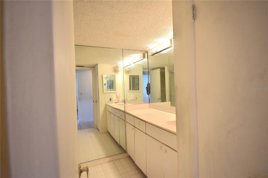 952 Virginia Street, Unit 107 Dunedin, FL 34698 - Photo 6 of 15 a large white bathroom with a large mirror vanity and shower