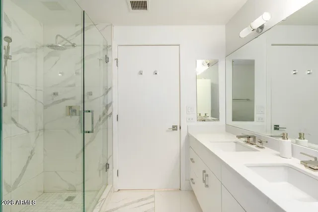 a bathroom with a double vanity sink mirror and shower