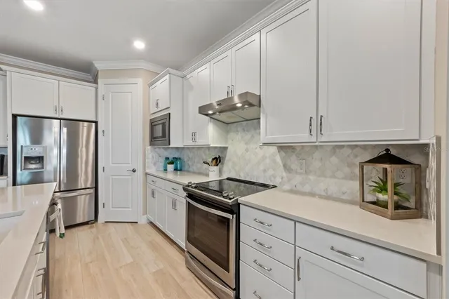a kitchen with stainless steel appliances granite countertop white cabinets and a refrigerator